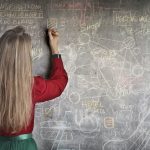 Femme qui écrit sur un tableau des signes mathématiques complexes